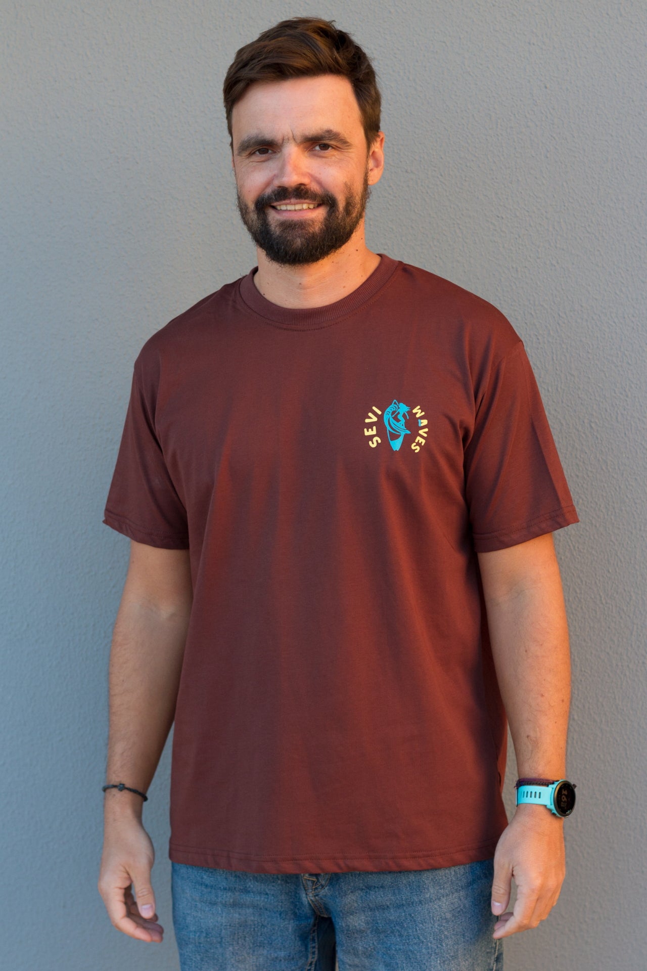 Man wearing a maroon t-shirt with a logo against a gray background