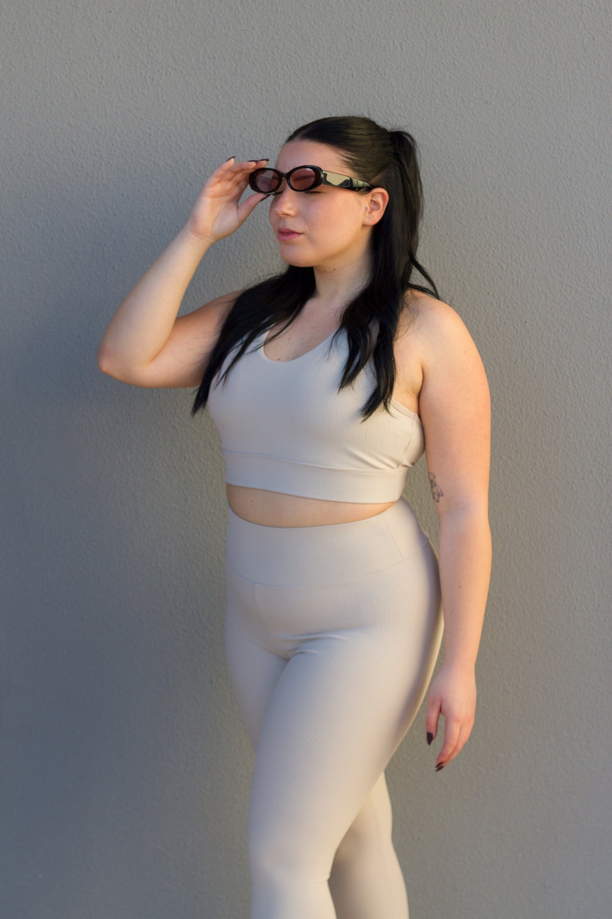Woman wearing a beige sports bra and leggings set against a plain background