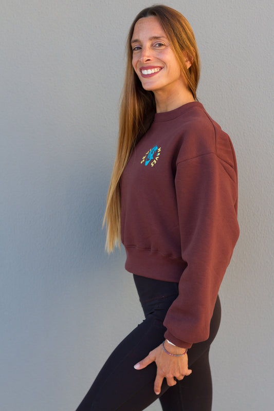 Woman wearing a maroon sweatshirt with a colorful design on a plain background