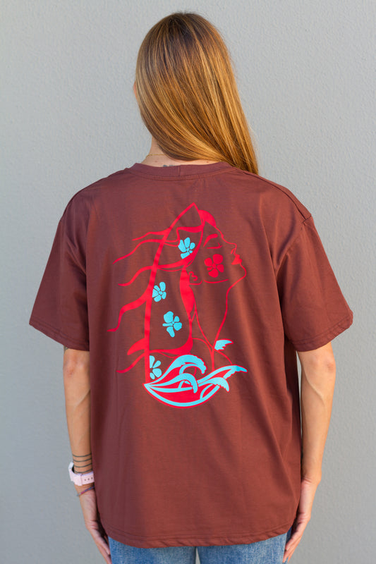 Person wearing a brown t-shirt with a red and blue graphic design on the back against a gray background