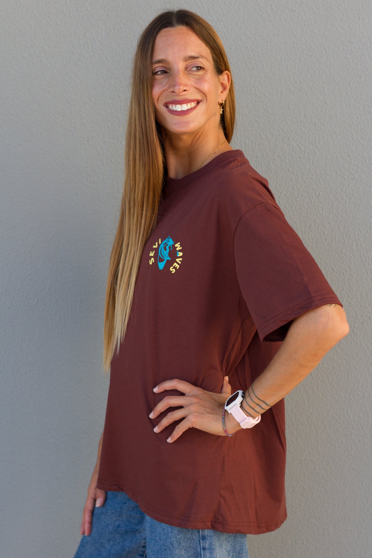Woman wearing a maroon t-shirt with a colorful design against a gray background made in greece