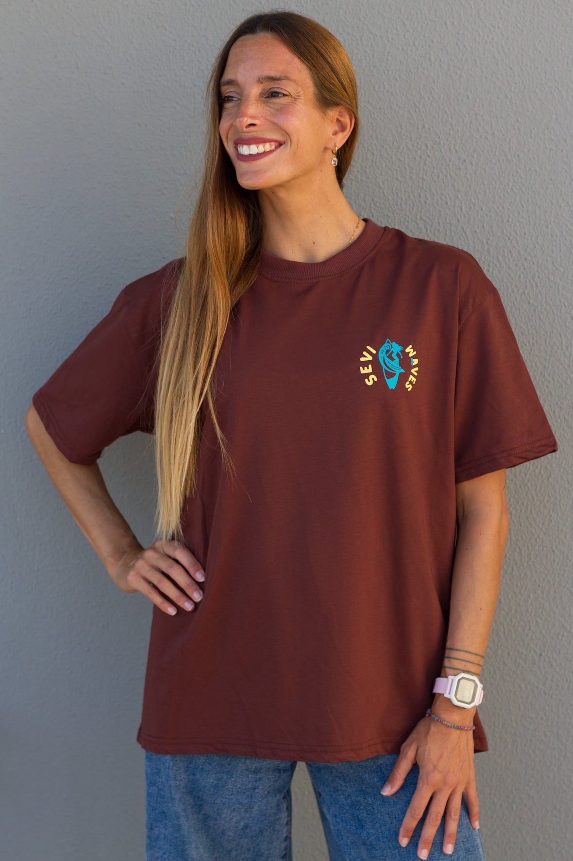 Woman wearing a maroon t-shirt with a colorful graphic design against a gray background