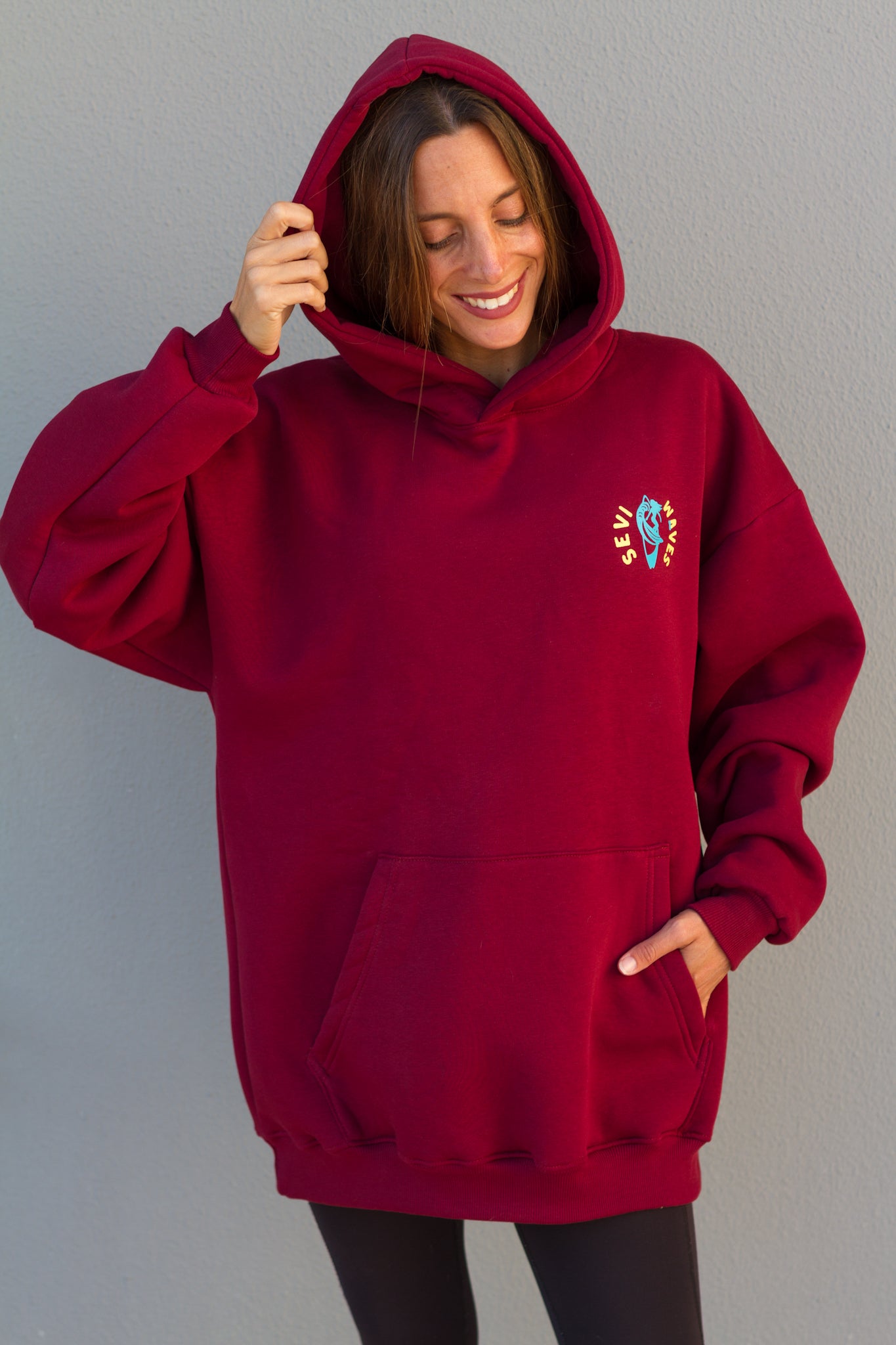 Person wearing a red hoodie with a small design on a plain background