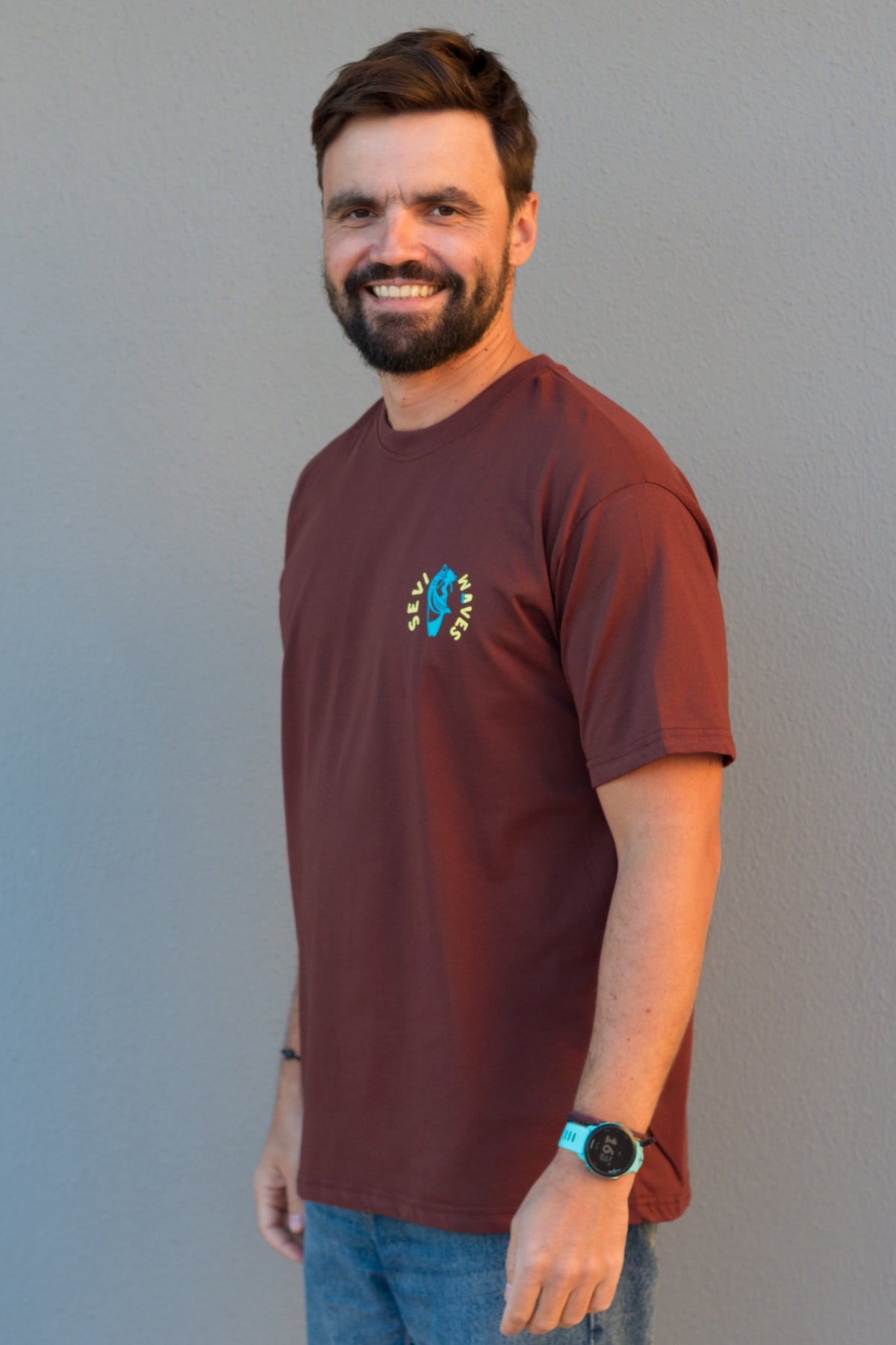Man wearing a maroon t-shirt with a logo against a plain background