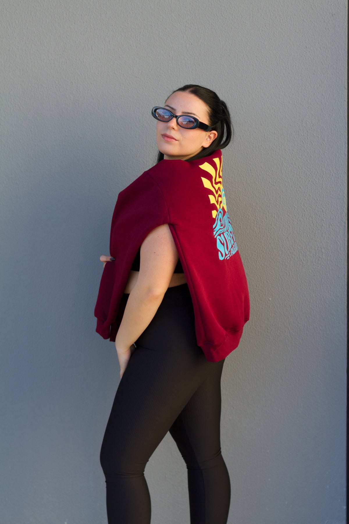 Person wearing a red hoodie with a colorful design on a plain background