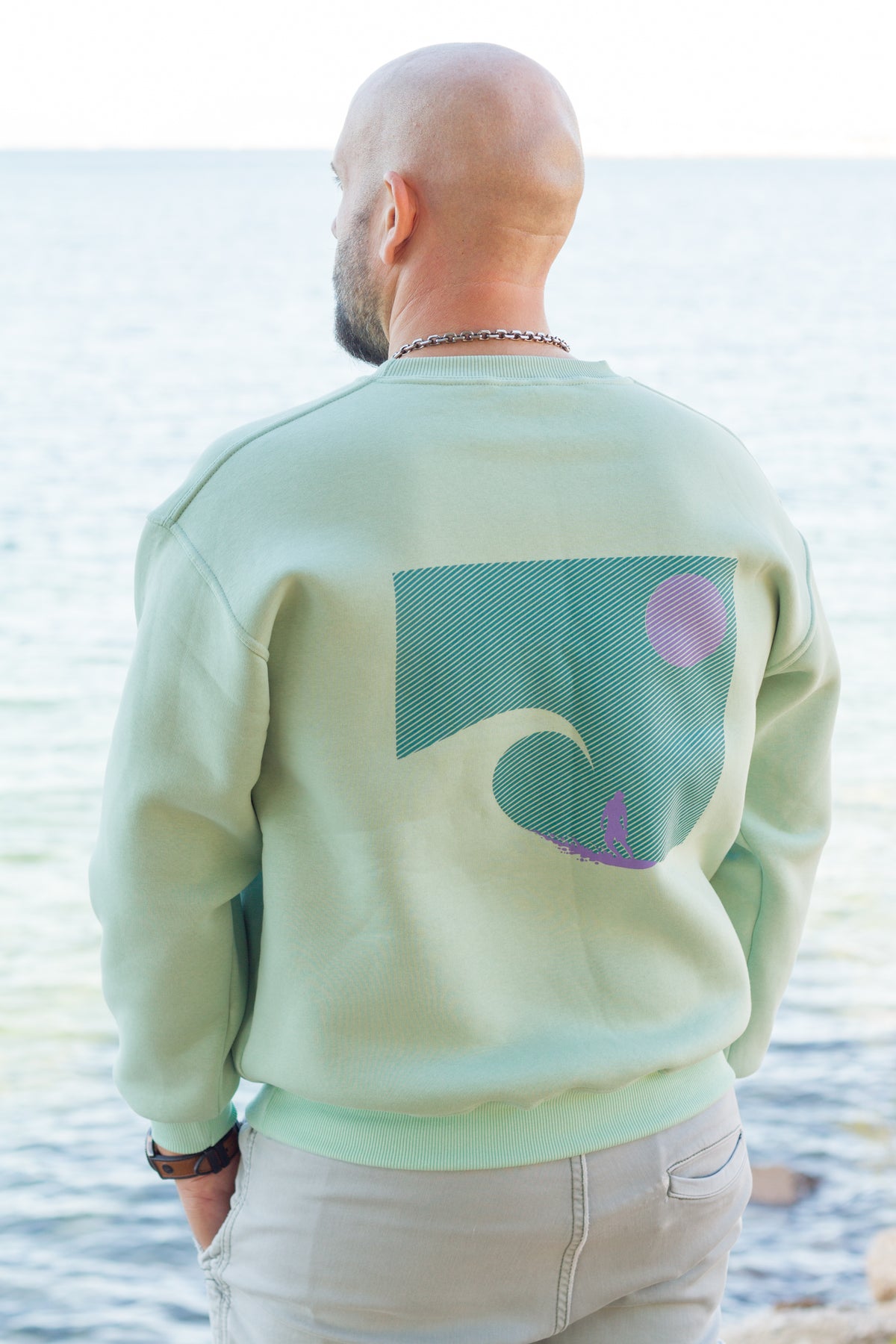Sevi Waves mint oversized crewneck sweatshirt with surfer riding a big wave at sunset.