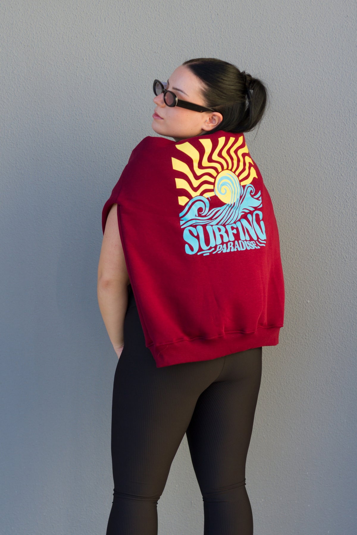 Person wearing a red hoodie with a graphic design on the back against a plain background