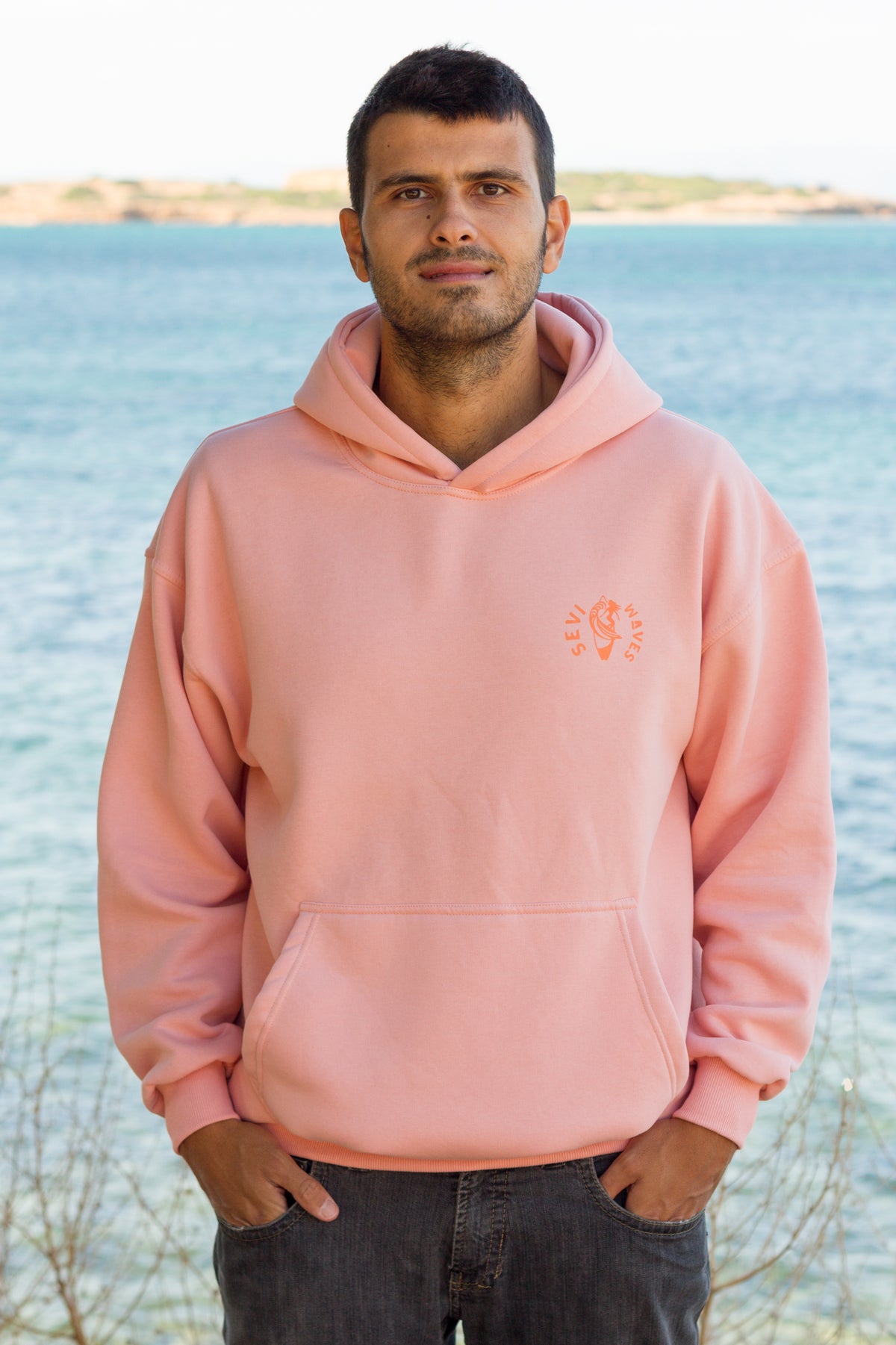 Retro surf style salmon hoodie featuring a large sunset and wave illustration.