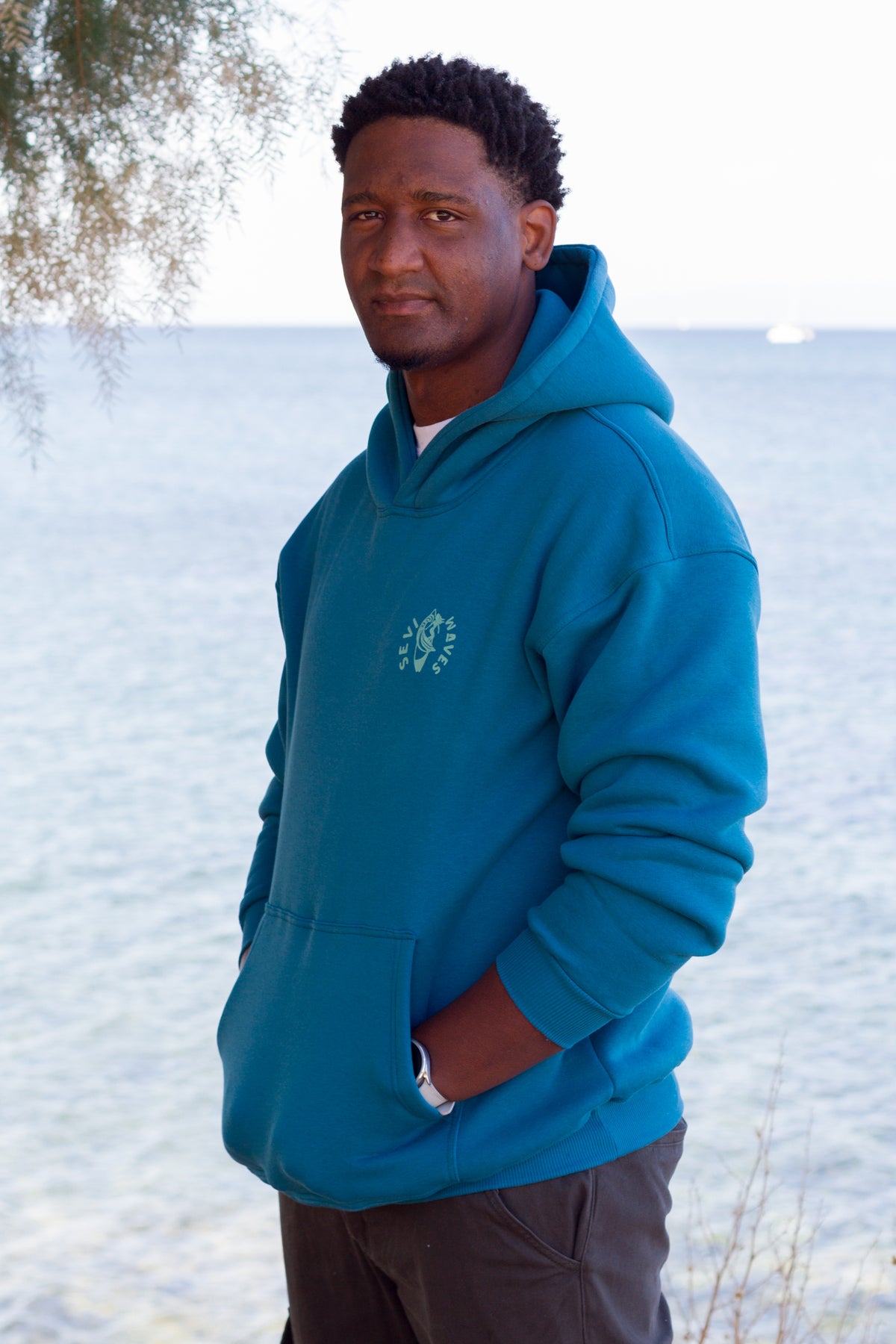Oversized petrol hoodie with a vintage-style big wave at sunset graphic, Sevi Waves collection.