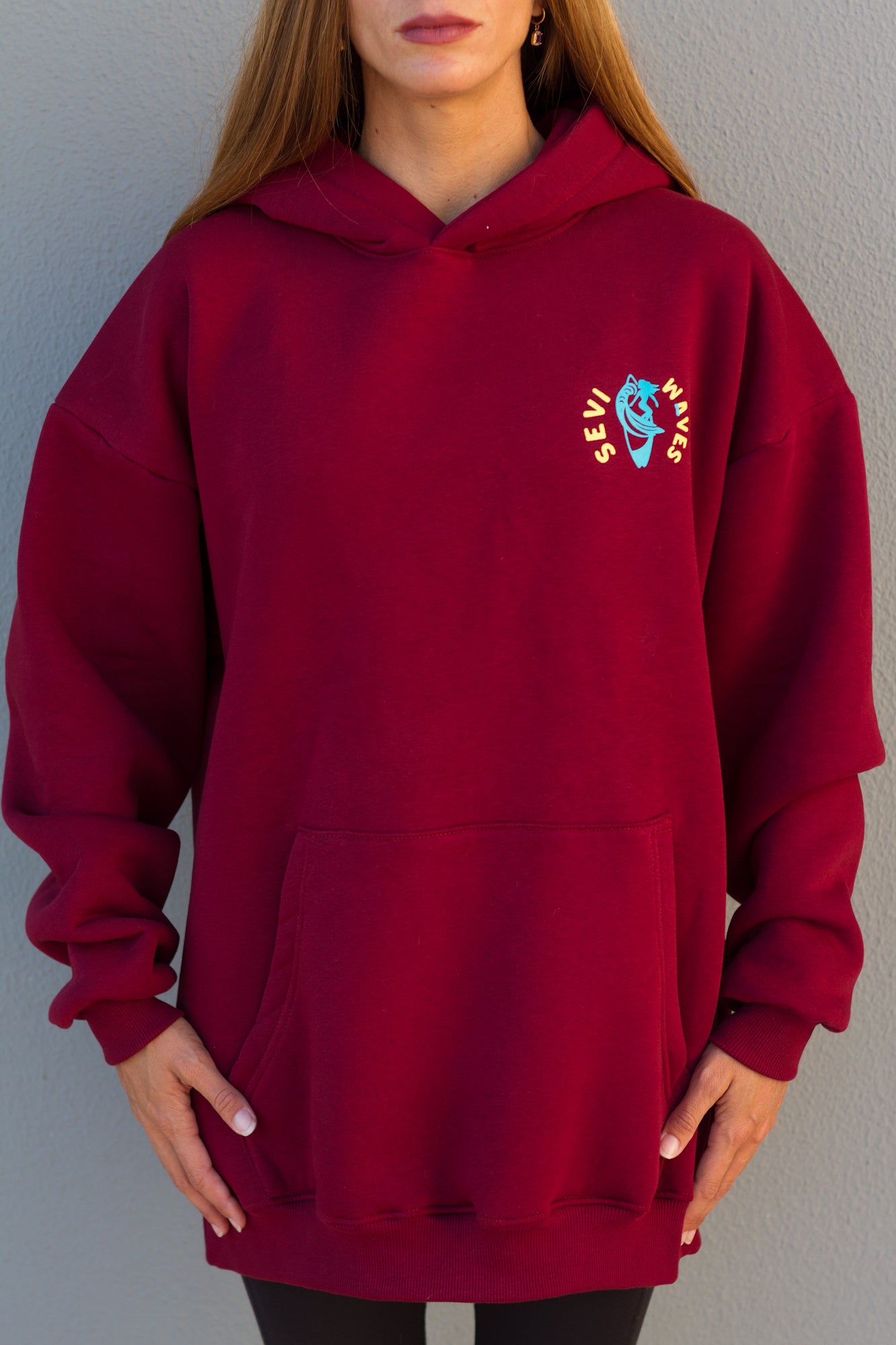 Red hoodie with a logo on the chest against a gray background