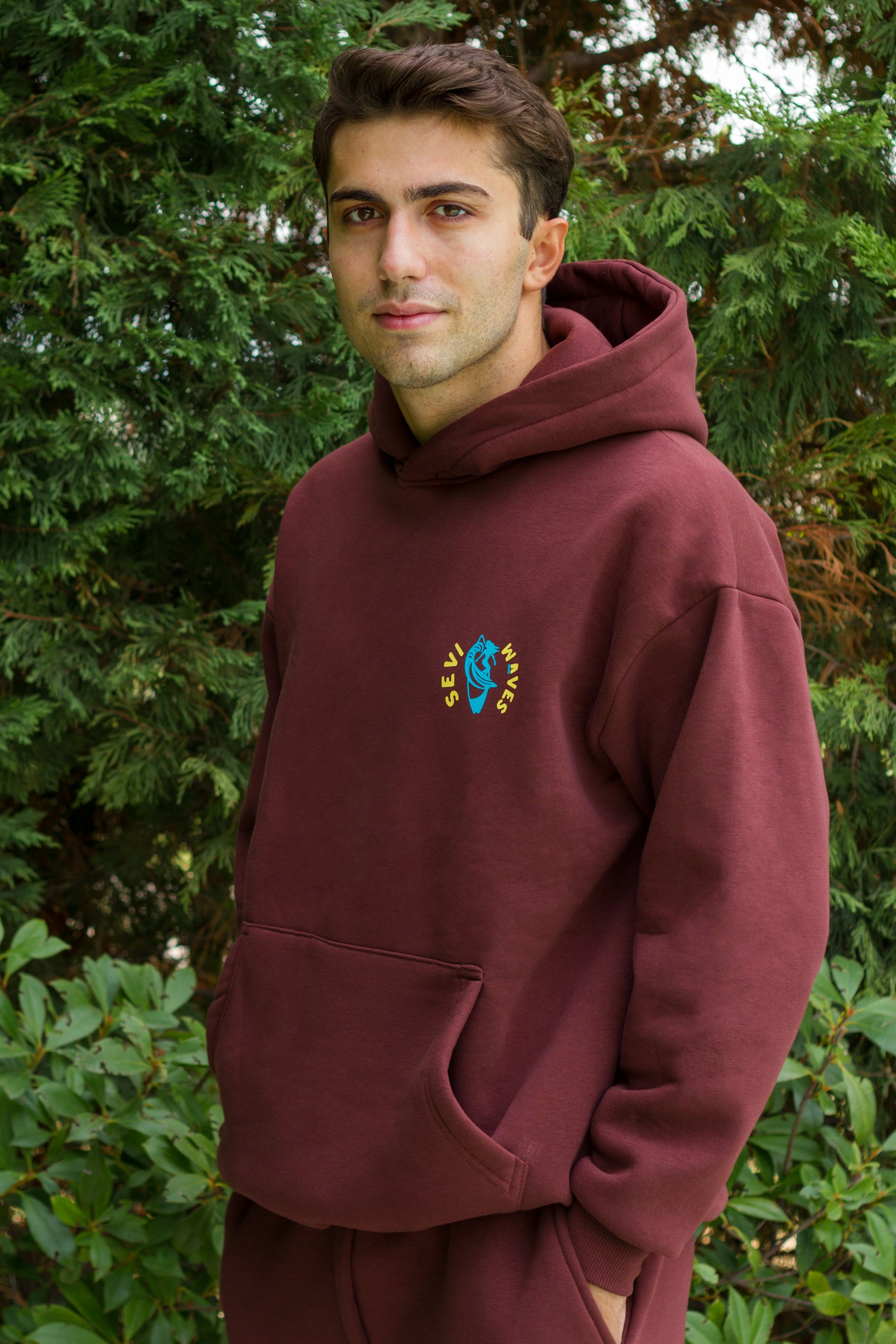 Man wearing a maroon hoodie with a custom  logo outdoors