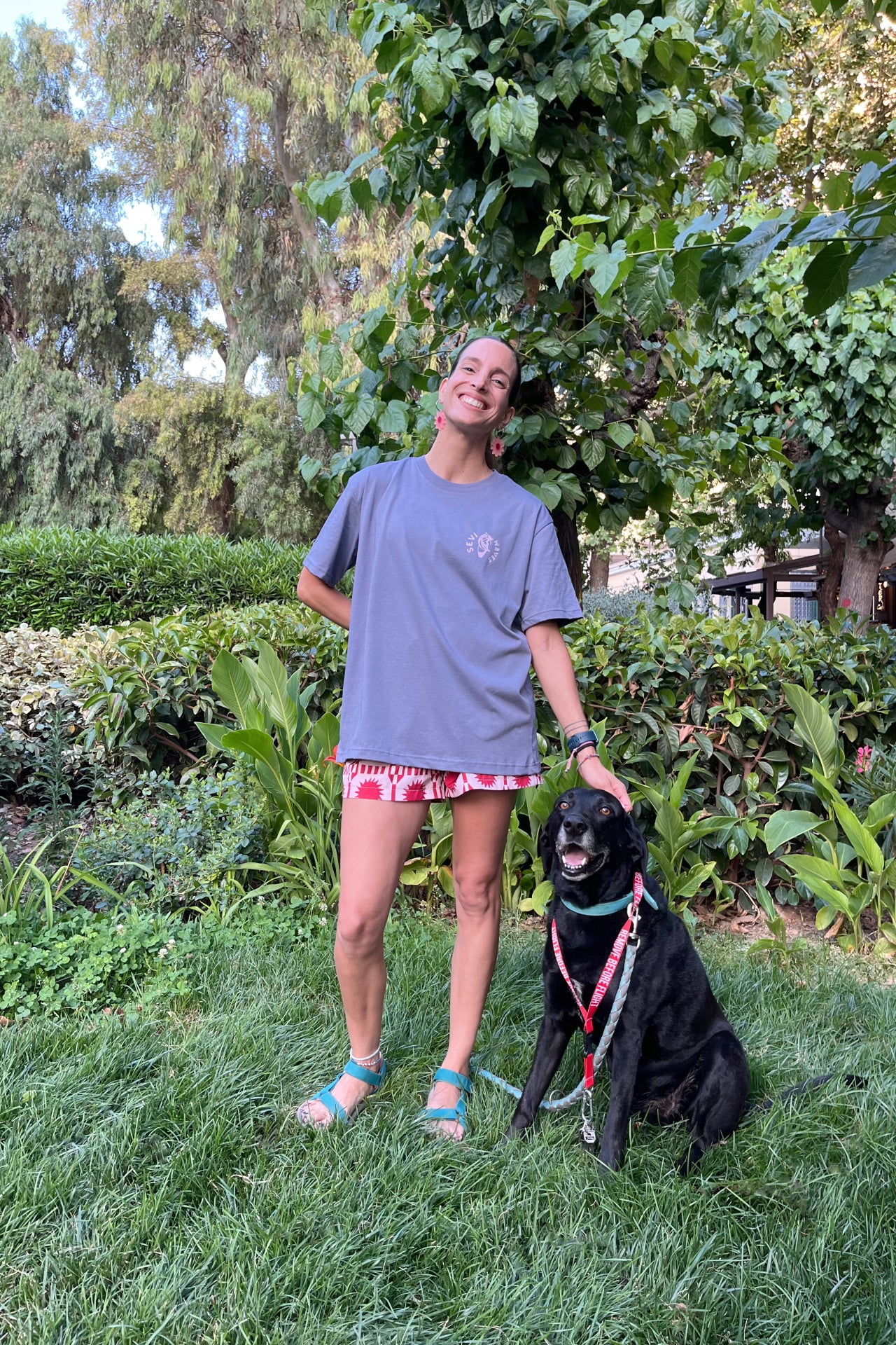 Woman standing with a black dog on a leash in a garden