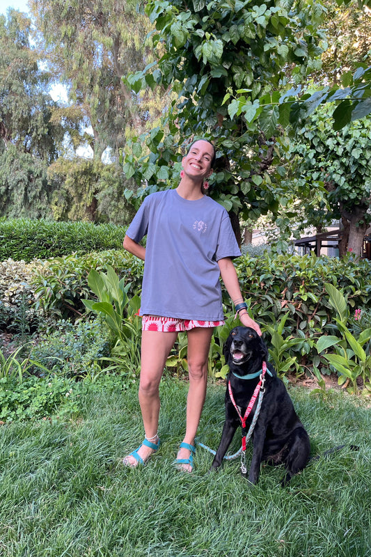 Woman standing with a black dog on a leash in a garden