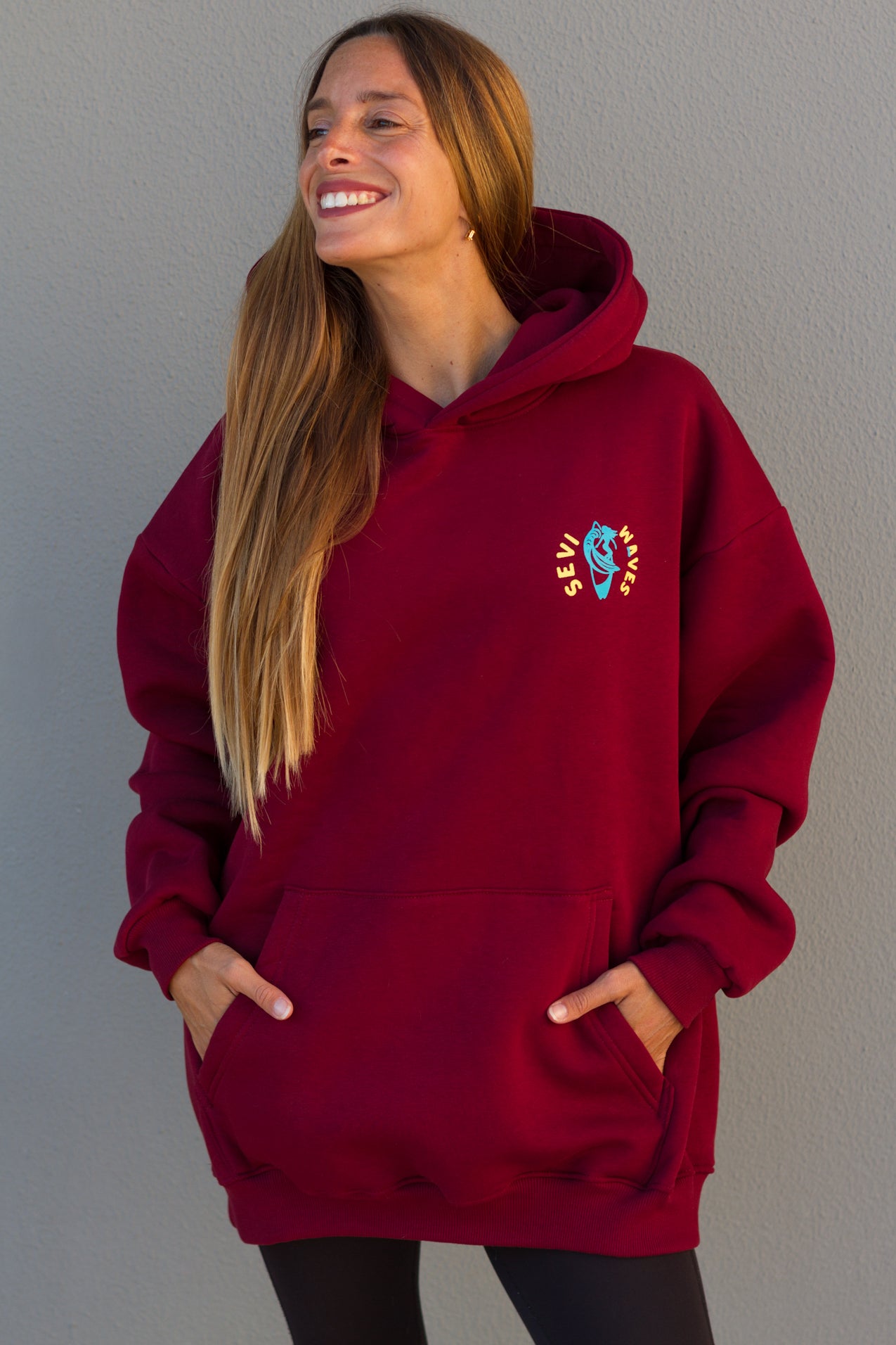 Woman wearing a red hoodie with a logo against a gray background