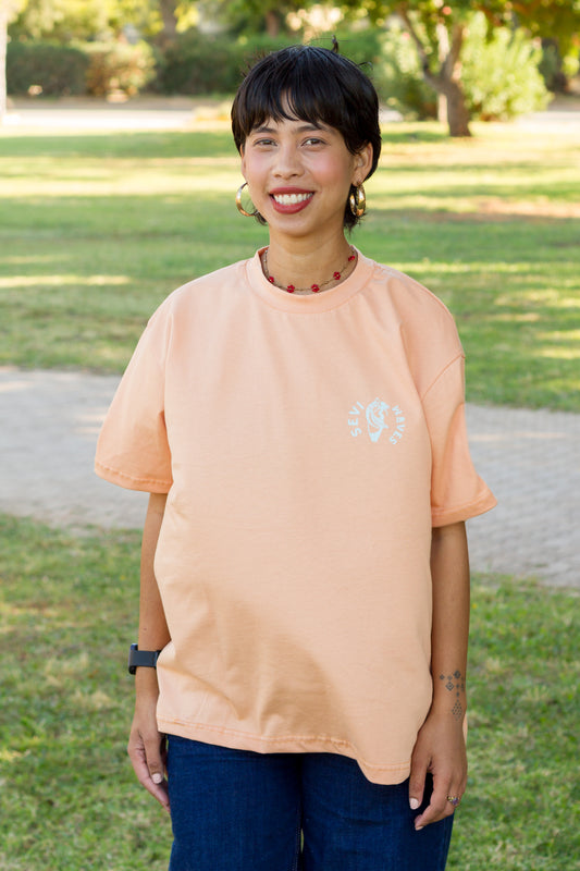 A woman wearing a light peach crewneck t-shirt by Sevi Waves  from the new collection
