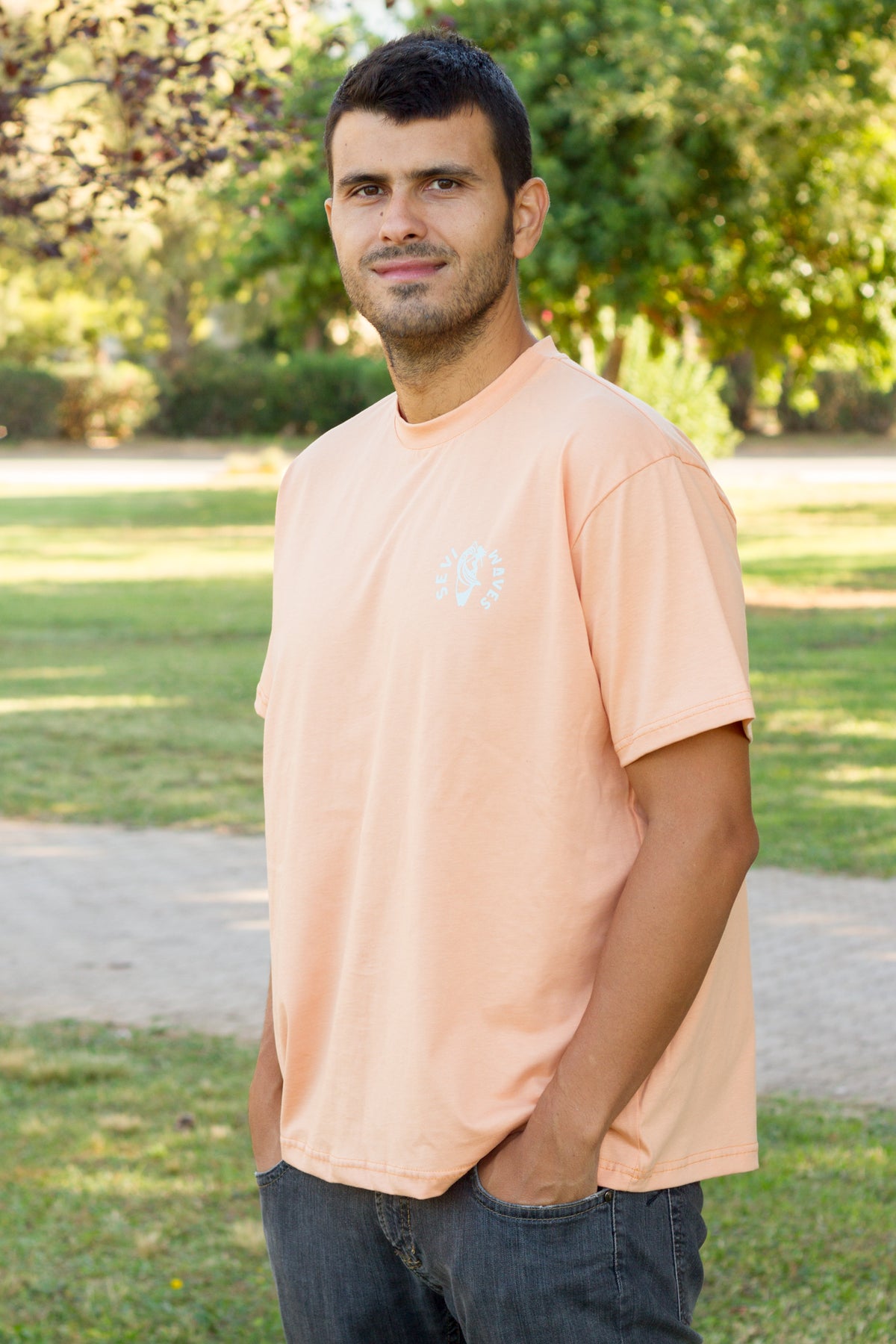 A man wearing a peach-colored crewneck t-shirt with logo Sevi Waves  