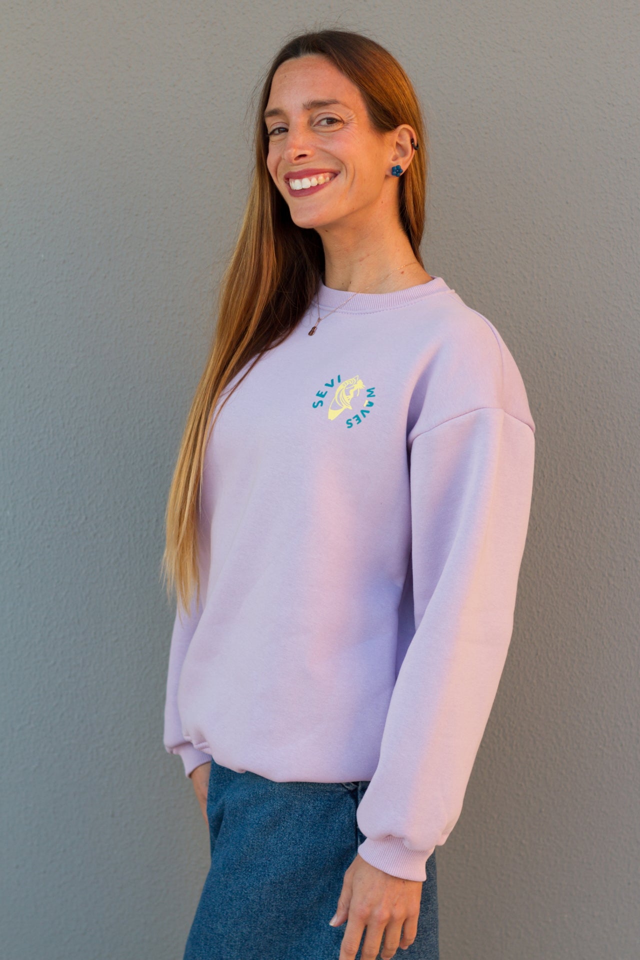 Woman wearing a light purple sweatshirt with a colorful design on a plain background