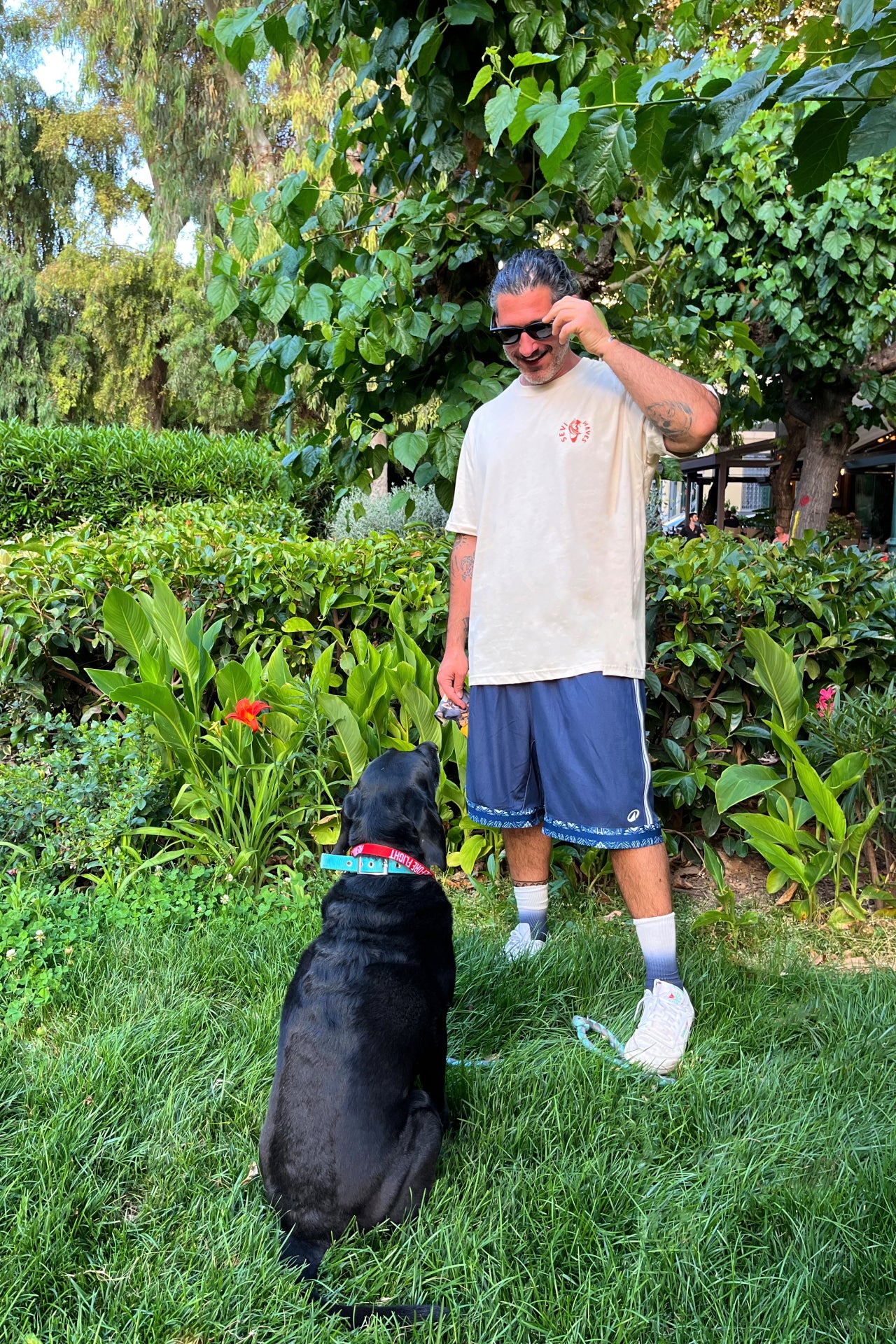 Man taking a selfie with a black dog in a garden