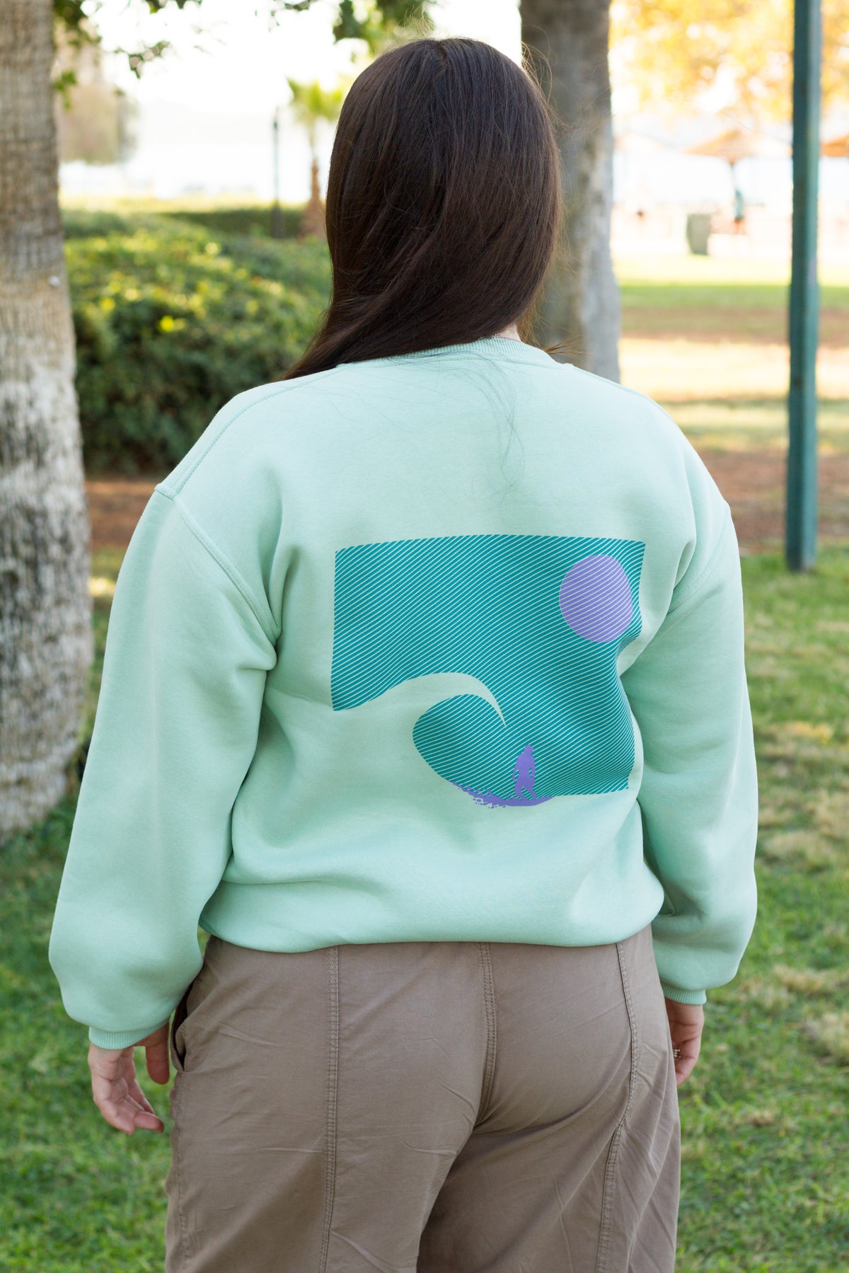 Sevi Waves mint oversized crewneck sweatshirt with surfer riding a big wave at sunset.