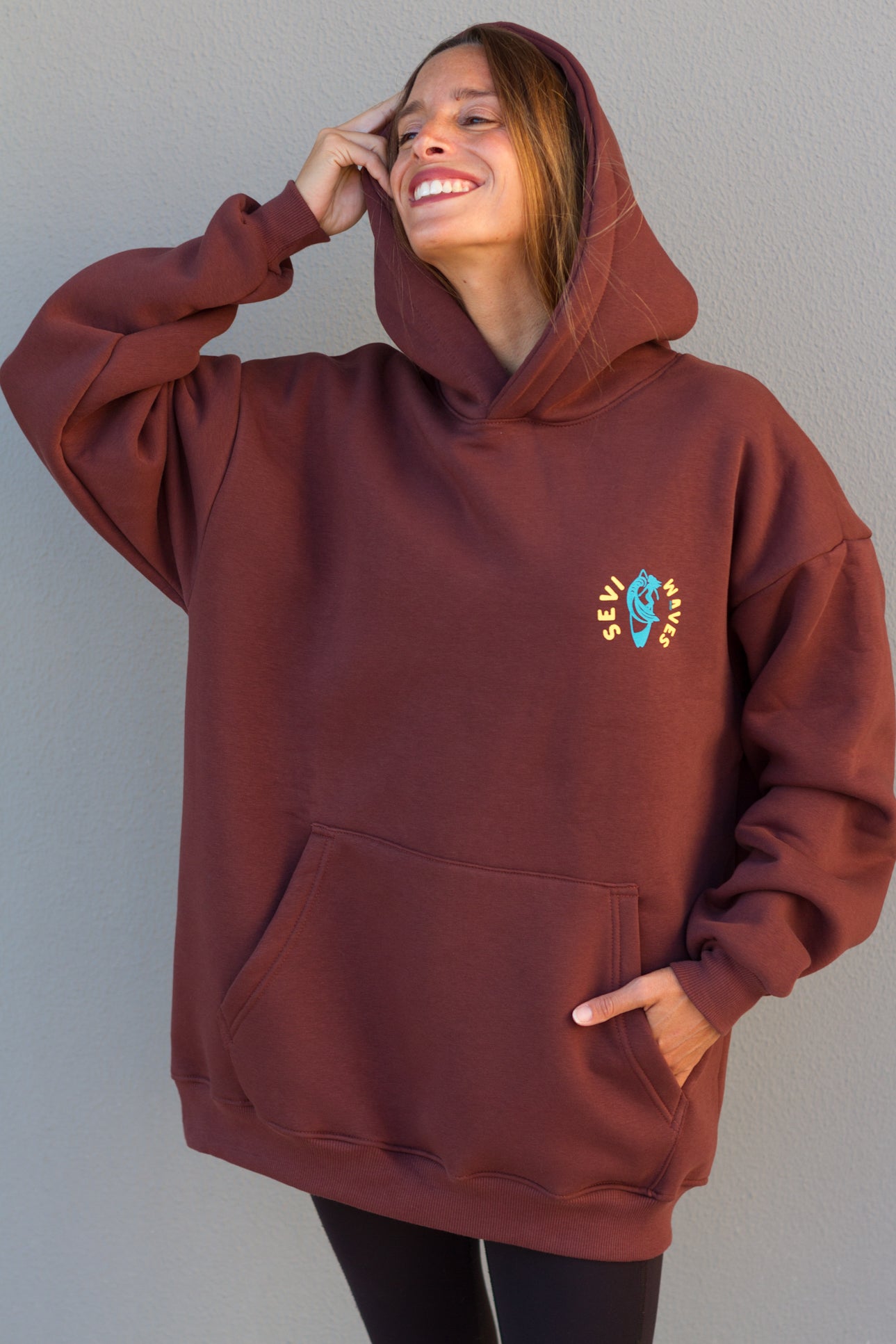 Person wearing a maroon hoodie with a small design on a plain background