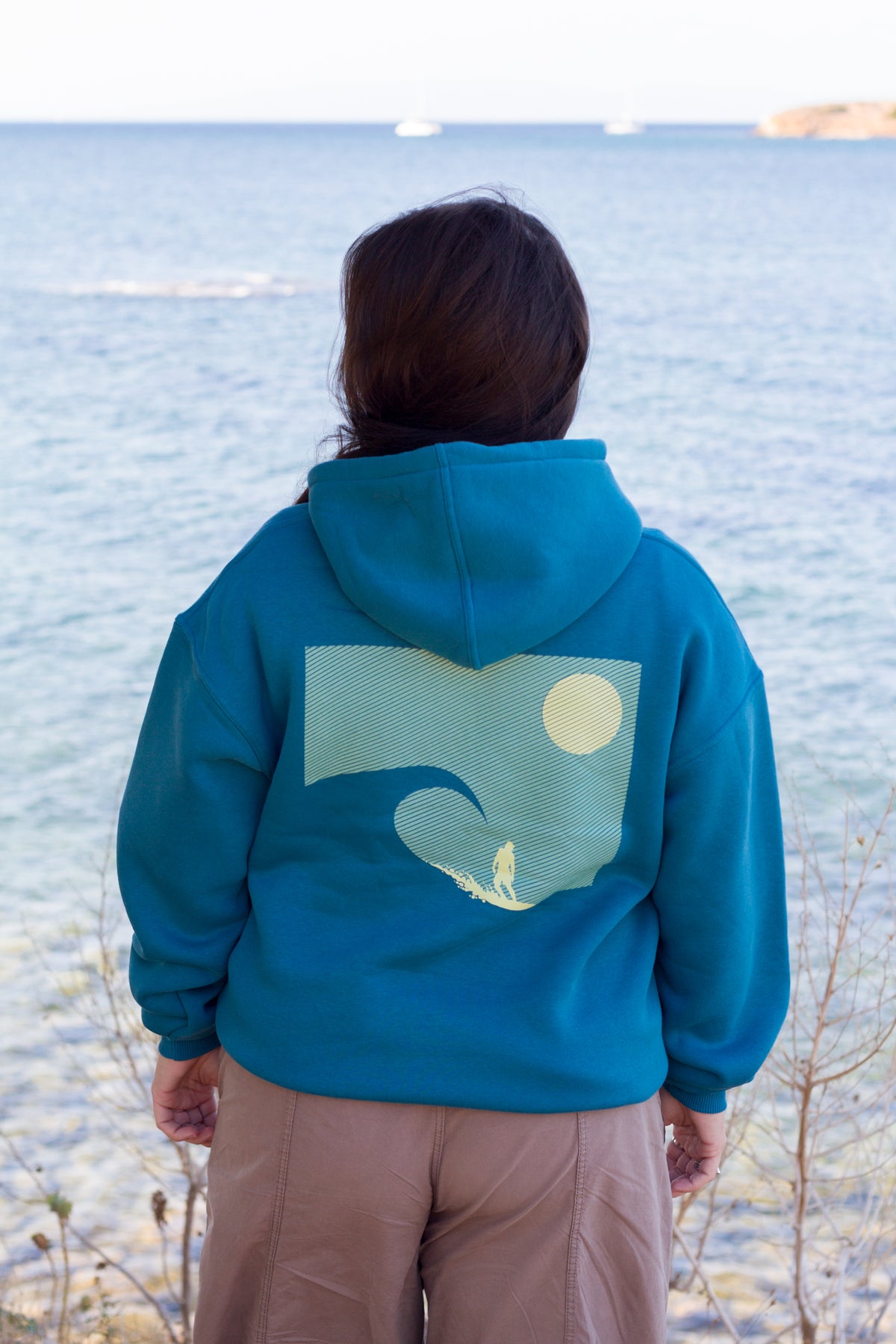 Close-up of the back print on the petrol blue Sevi Waves oversized hoodie.