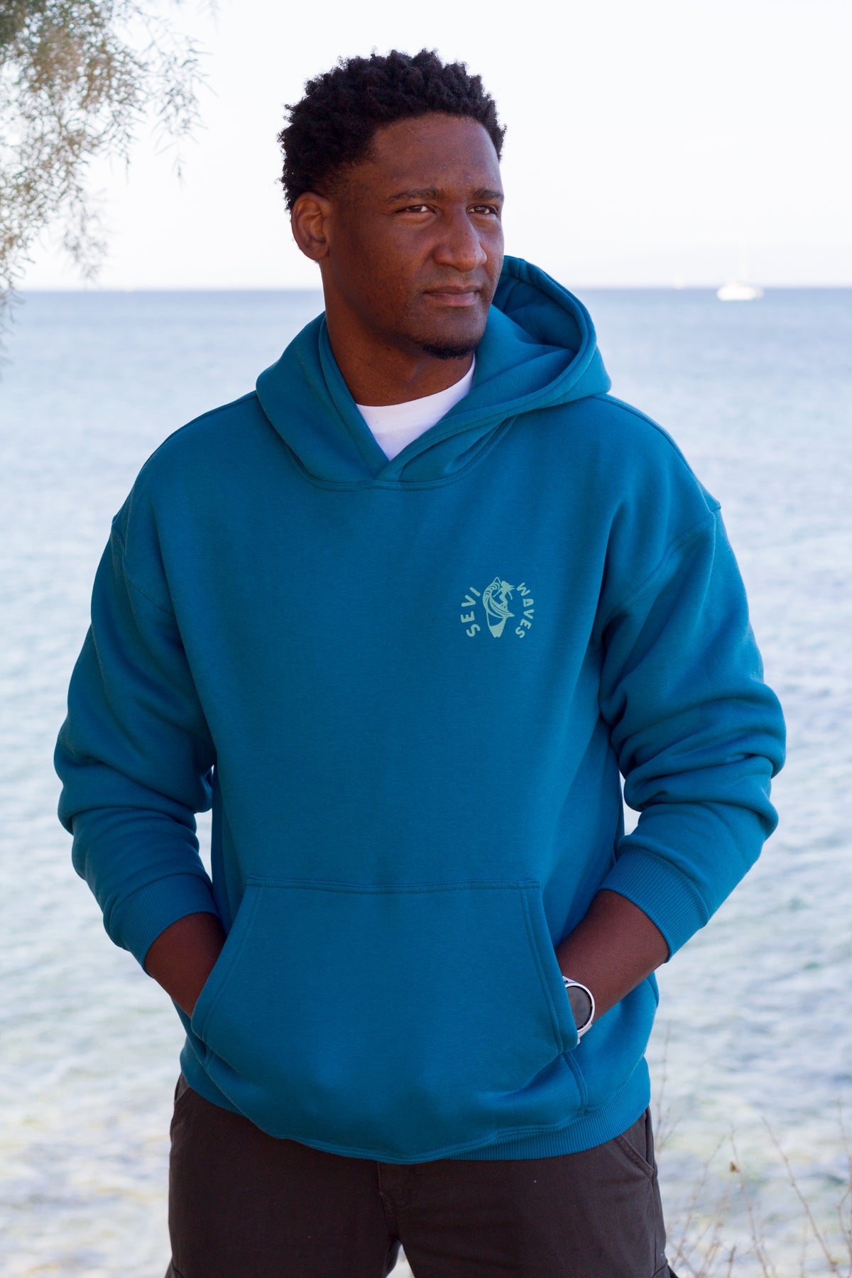 Petrol blue oversized hoodie with a retro-inspired ocean wave graphic by Sevi Waves.